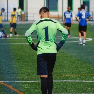 Young soccer goalkeeper on the field during a lively youth match.