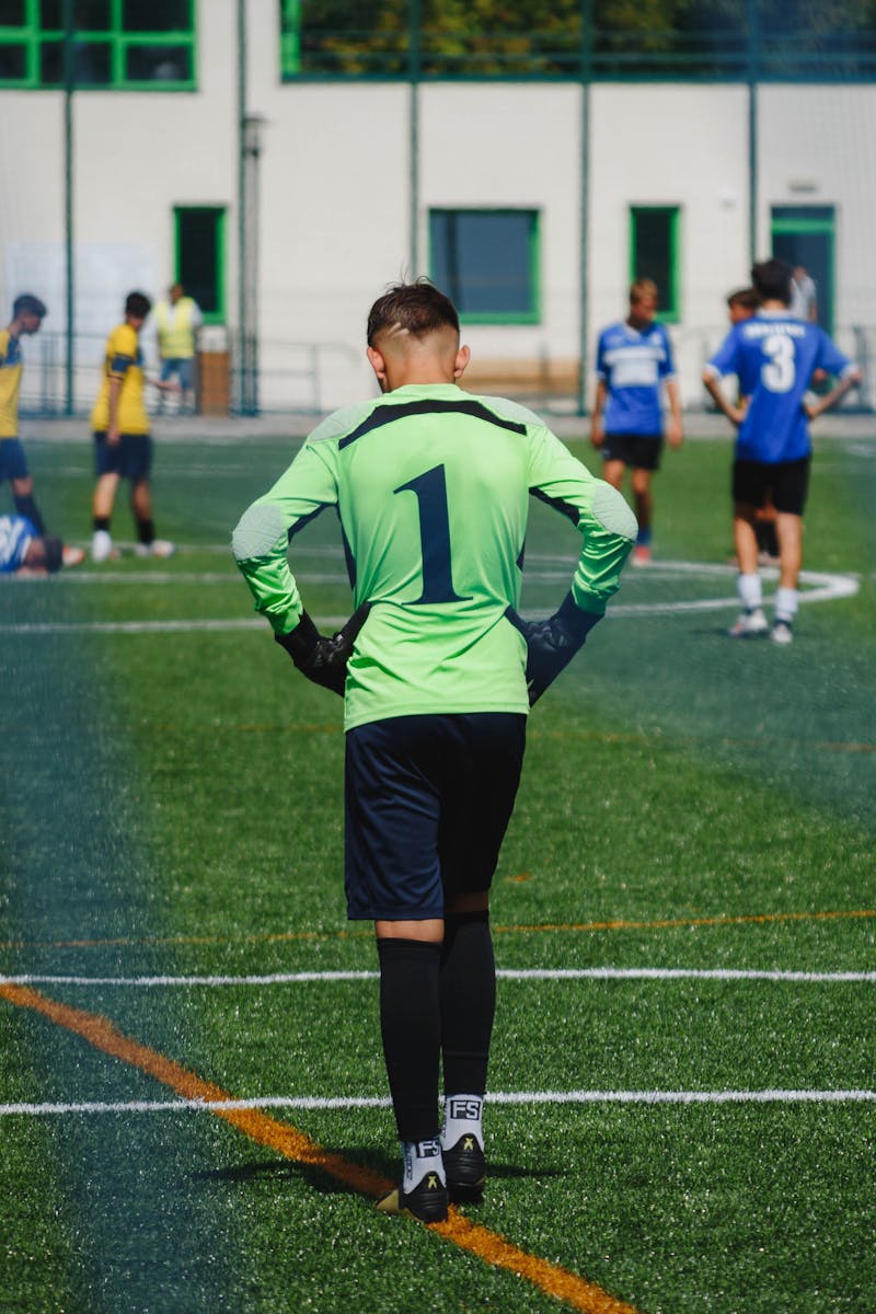 Young soccer goalkeeper on the field during a lively youth match.